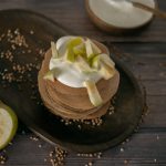 From above of tasty homemade pancakes made of buckwheat topped with sour cream and apples served on wooden table in kitchen
